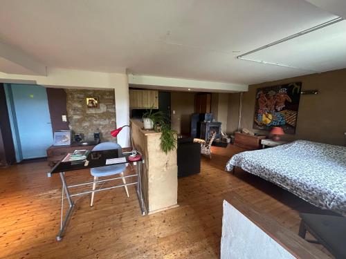 a bedroom with a bed and a desk in a room at Au mont des Brumes in Stoumont