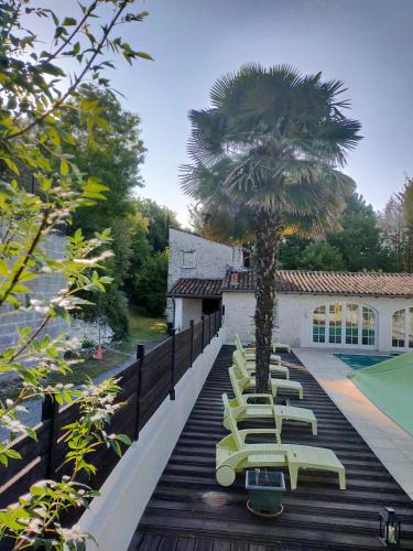 une rangée de chaises longues et un palmier sur une terrasse dans l'établissement Villa 168m2 Piscine Parc Arboré pour groupe Famille Amis jusqu'à 10 personnes, à Courcoury