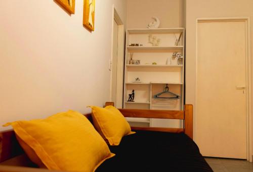 a bedroom with a bed with yellow pillows and a shelf at LOS GURISES Villa Elisa in Villa Elisa