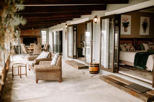 a living room with a bed and a couch and chairs at Breathe Accommodation in Oudtshoorn