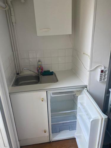 a small kitchen with a sink and an empty refrigerator at Studio 300m de la plage in Le Havre