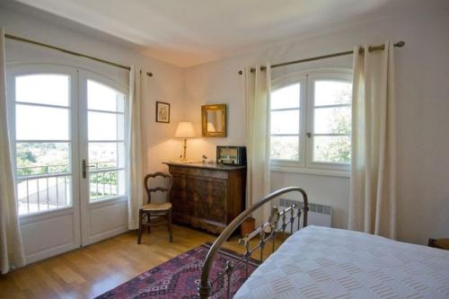a bedroom with a bed and two windows and a desk at Le Cheval Blanc in Vauvert