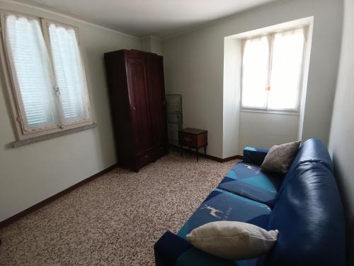 a living room with a blue couch and two windows at I 3 Moschettoni in Valbrona