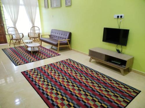 a living room with a couch and a tv and a rug at Sobey Laris Homestay QASEH in Pasir Mas