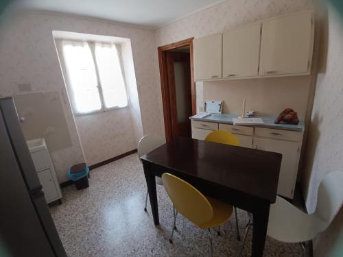 a kitchen with a black table and yellow chairs at I 3 Moschettoni in Valbrona