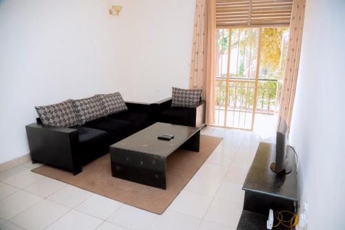 a living room with a black couch and a table at Cosy Hidden Gem in Kigali