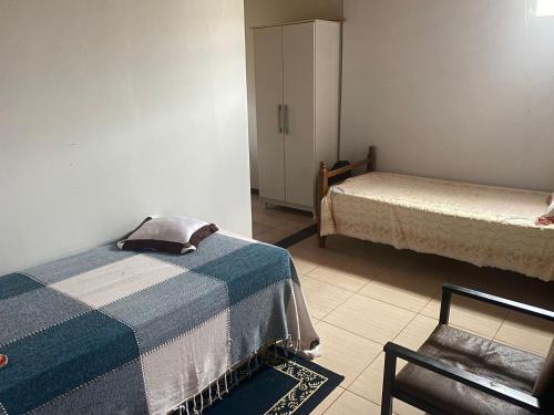 a room with two beds and a cabinet in it at Quarto em Foz do Iguaçu in Foz do Iguaçu