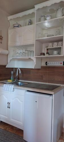 a kitchen with white cabinets and a sink at GaLiBa Vendégház in Jenő