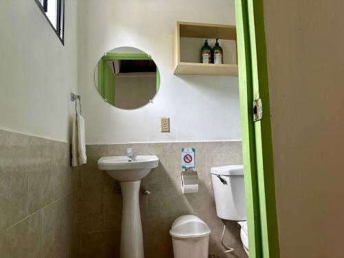 a bathroom with a sink and a toilet and a mirror at Hotel Zelen in Tamanique