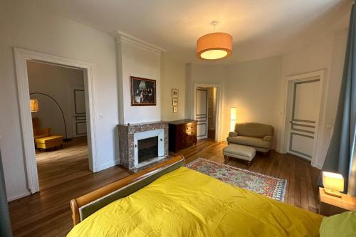 1 dormitorio con cama amarilla y chimenea en Proche Vittel et Contrexéville château Viendal et son beau parc, 