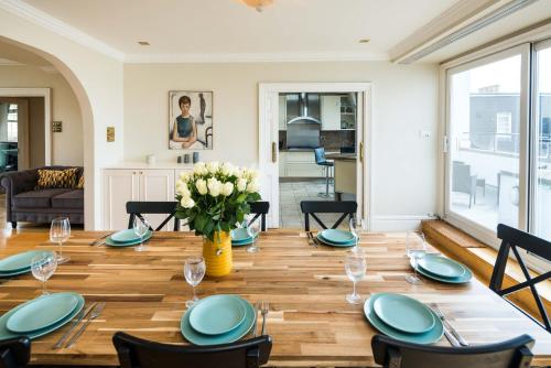 a dining room table with a vase of flowers at Kensington Skyline Penthouse in London