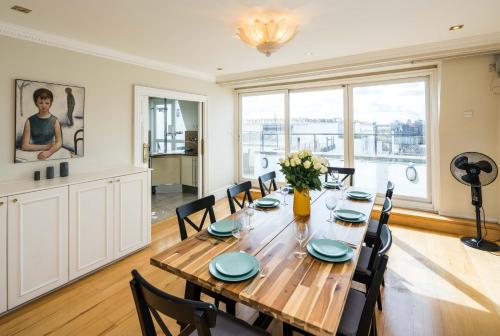 a dining room with a wooden table and chairs at Kensington Skyline Penthouse in London