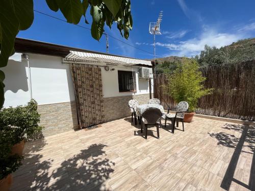 a patio with a table and chairs and a fence at Cortijo Los Cahorros Sierra Nevada in Monachil