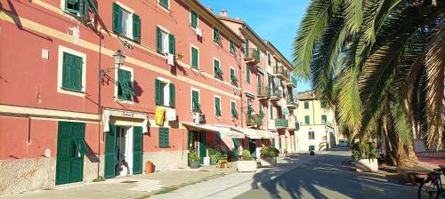 una calle con edificios rosados y verdes y una palmera en A UN PASSO DAL MARE, en Riva Trigoso