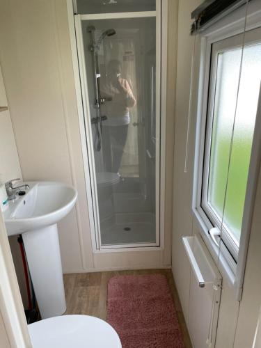 een badkamer met een douche, een toilet en een wastafel bij Emeralds caravan lettings in Selsey