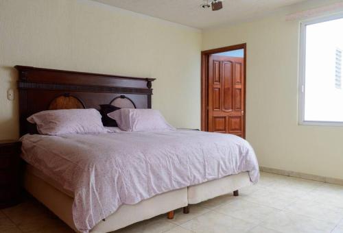 - une chambre avec un grand lit et une tête de lit en bois dans l'établissement Departamento en el Centro de Morelia, à Morelia
