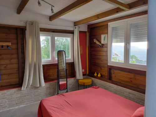 - une chambre avec un lit rouge et deux fenêtres dans l'établissement Douceur des Hauteurs bas de villa, piscine privée, à Sainte-Luce