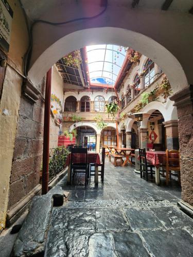 an archway in a building with tables and chairs at Pirwa Backpackers Colonial in Cusco
