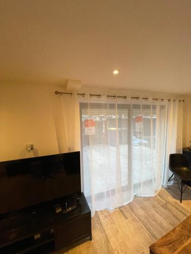 - un salon avec une fenêtre et des rideaux blancs dans l'établissement Studio proche Paris, à Vigneux-sur-Seine