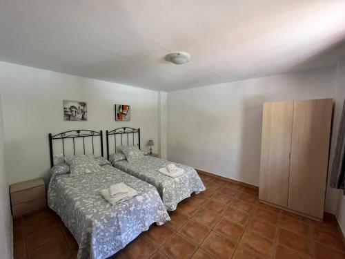a bedroom with two beds and a cabinet at Cortijo Los Cahorros Sierra Nevada in Monachil