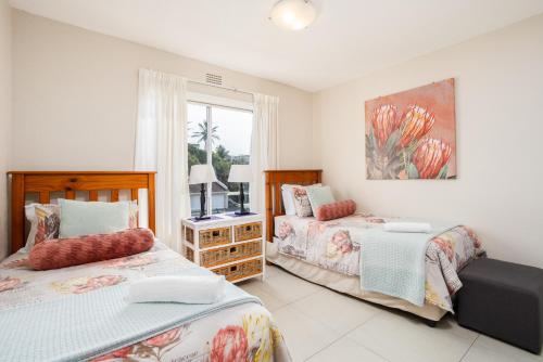 een slaapkamer met 2 bedden en een raam bij Laguna La Crete 6 in Uvongo Beach