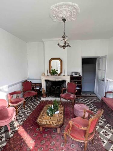 a living room with red chairs and a table at Villa coutrillonne près St Emilion [clim salon] in Coutras