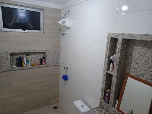 baño con espejo y TV en la pared en Aluga-se quarto em apartamento en Ipatinga