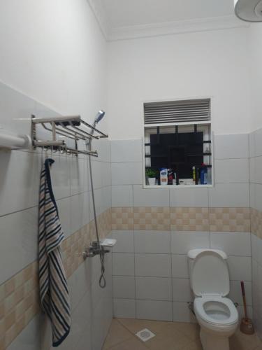 a bathroom with a toilet and a window at Freeve Suites Akright City Bwebajja in Buzzi