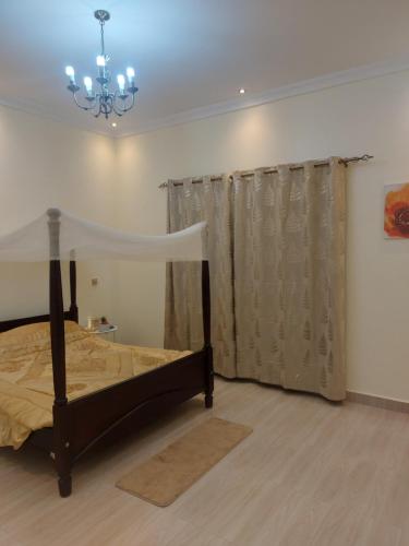a bedroom with a bed and a chandelier at Freeve Suites Akright City Bwebajja in Buzzi