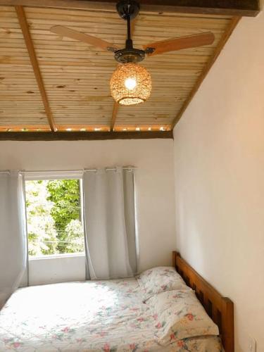 a bedroom with a ceiling fan and a bed with a window at Apto 1030 in Trancoso