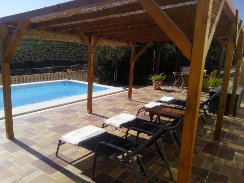 un patio con mesa y sillas junto a una piscina en Casa rural CAÑADA PAEZ, en Vélez-Málaga