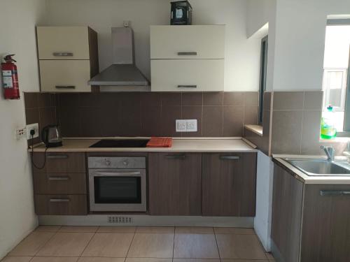 a kitchen with wooden cabinets and a stove top oven at you can enjoy your time at waterford apartment in Attard