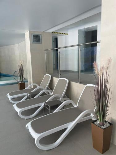 a row of white chairs in a room with a pool at StoneHill24 - Apartament & Spa in Szklarska Poręba