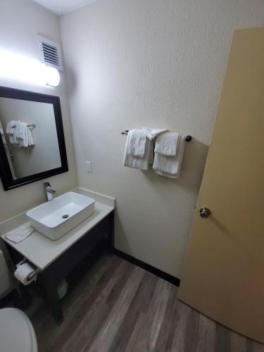 Jackson Hotel & Convention Center في جاكسون: حمام مع حوض ومرآة ومناشف