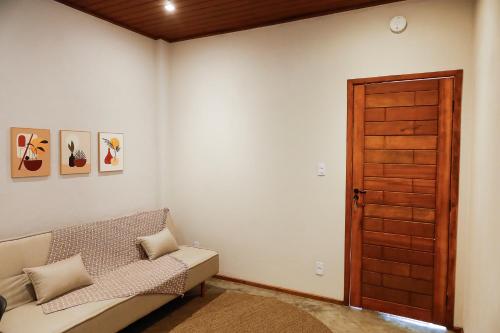 uma sala de estar com um sofá e uma porta de madeira em Vista do Vale lofts - Itaipava em Petrópolis