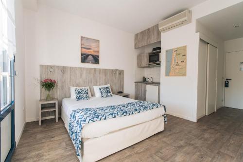 a bedroom with a bed with blue and white sheets at Hotel Mercedes in Hossegor