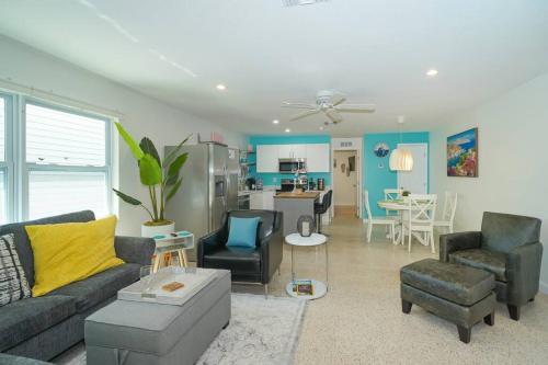 a living room with a couch and chairs and a kitchen at Modern, Fresh - Only 3 miles to the Beach! in Sarasota