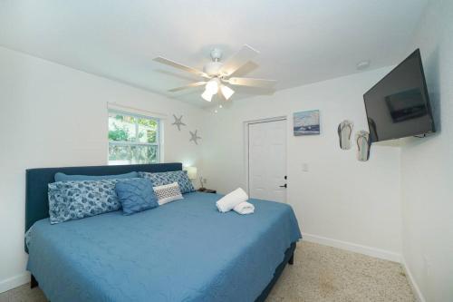 a bedroom with a blue bed and a ceiling fan at Modern, Fresh - Only 3 miles to the Beach! in Sarasota