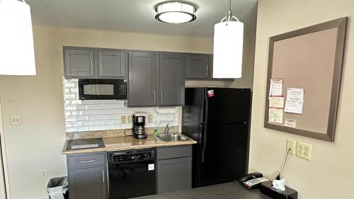 a kitchen with a black refrigerator and a sink at Candlewood Suites South Bend Airport by IHG in South Bend