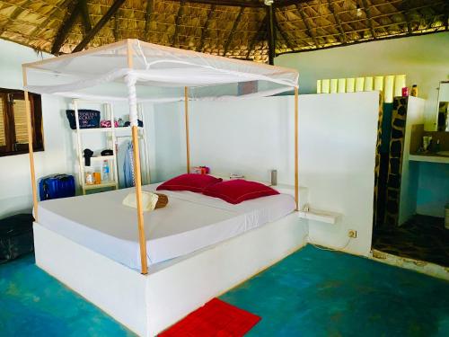 um quarto com uma cama de dossel branca com almofadas vermelhas em Mitsio Paradise - Hotel privatif en pension complète em Nosy Mitsio