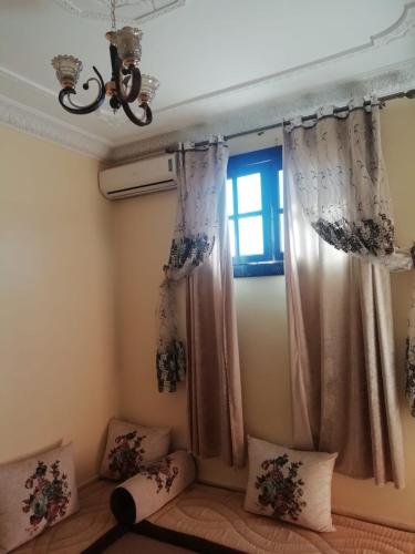 um quarto com uma janela com cortinas e almofadas em شقة بجنب مطار المسيرة 