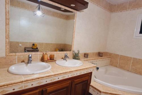 een badkamer met 2 wastafels, een bad en een spiegel bij L'escapade sauvage in Saint-Joseph