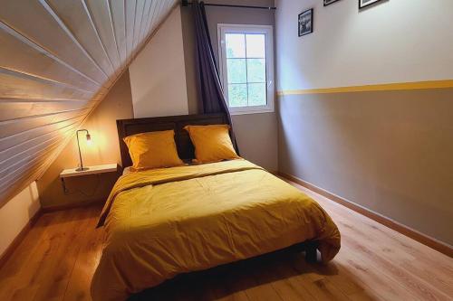 1 dormitorio con 1 cama con sábanas amarillas y ventana en L'escapade sauvage en Saint-Joseph