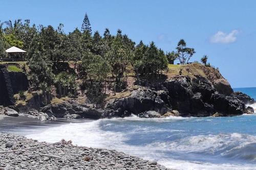 a rocky beach with a house on top of a cliff at Bienvenue a la marine Saint benoit 2 in Saint-Benoît