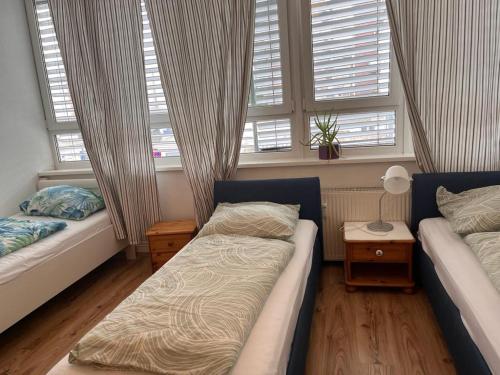 a bedroom with two beds and two windows at Hotel Wandsbek Hamburg in Hamburg
