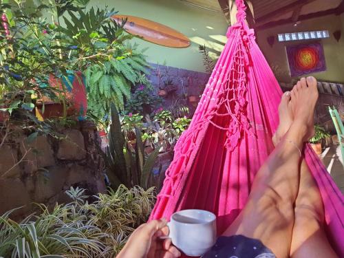 a woman laying on a hammock with her feet up at Joaquina 433 - Pousada Floripa in Florianópolis
