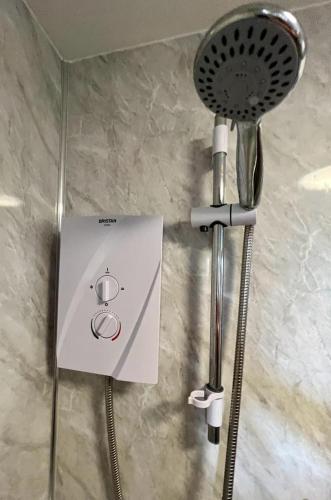 a shower head and a hair dryer on a wall at Tailte Trá in Carnlough