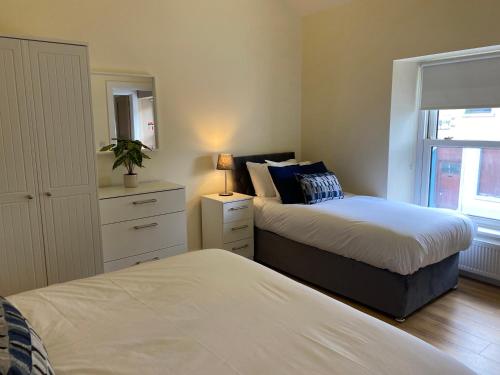 a bedroom with two beds and a dresser and a window at Church View House in Kells