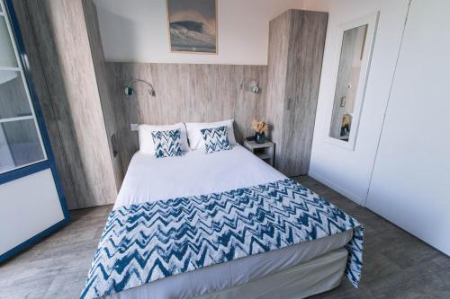 a bedroom with a large bed with blue and white sheets at Hotel Mercedes in Hossegor