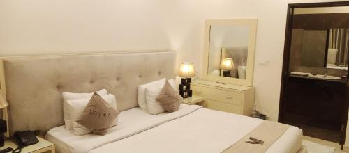 a bedroom with a white bed with pillows and a mirror at MaryLeena Hotel Gulberg in Gulberg
